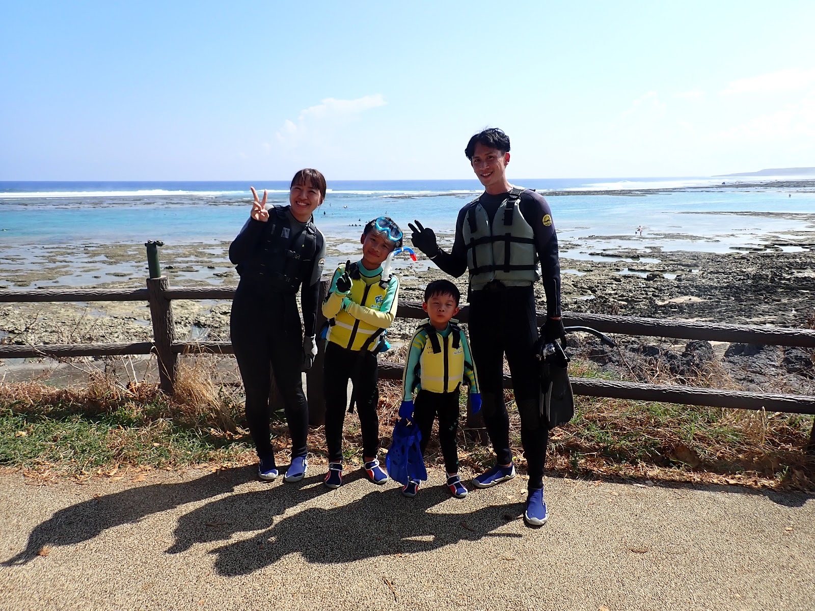 過去のツアーで撮影した青い空と海を背景に笑顔でポーズをとる家族連れ