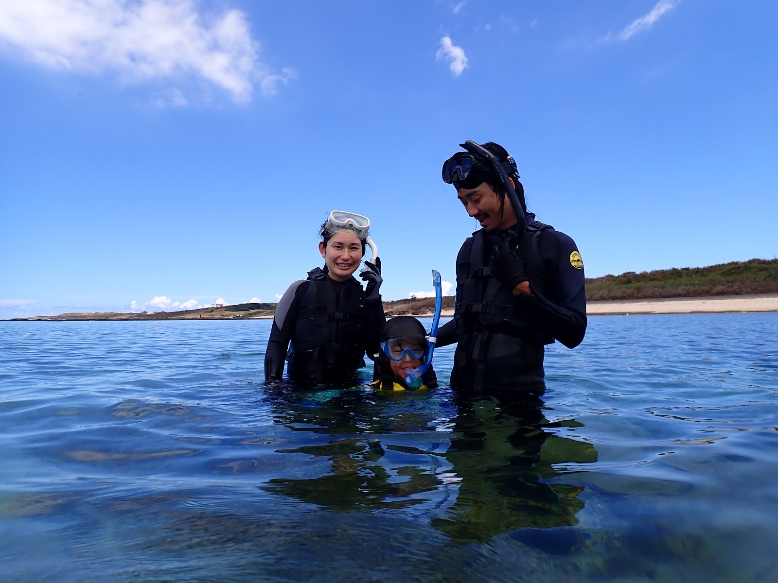 過去のツアーで撮影した親子連れのお客様が海に入りガイドと談笑する様子