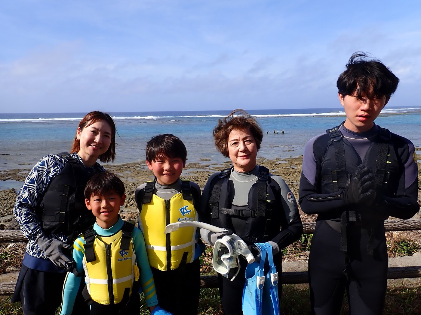 天然水族感で紹介する、青い空と海を背景にシュノーケルウェアを着用した参加者が笑顔で写る集合写真