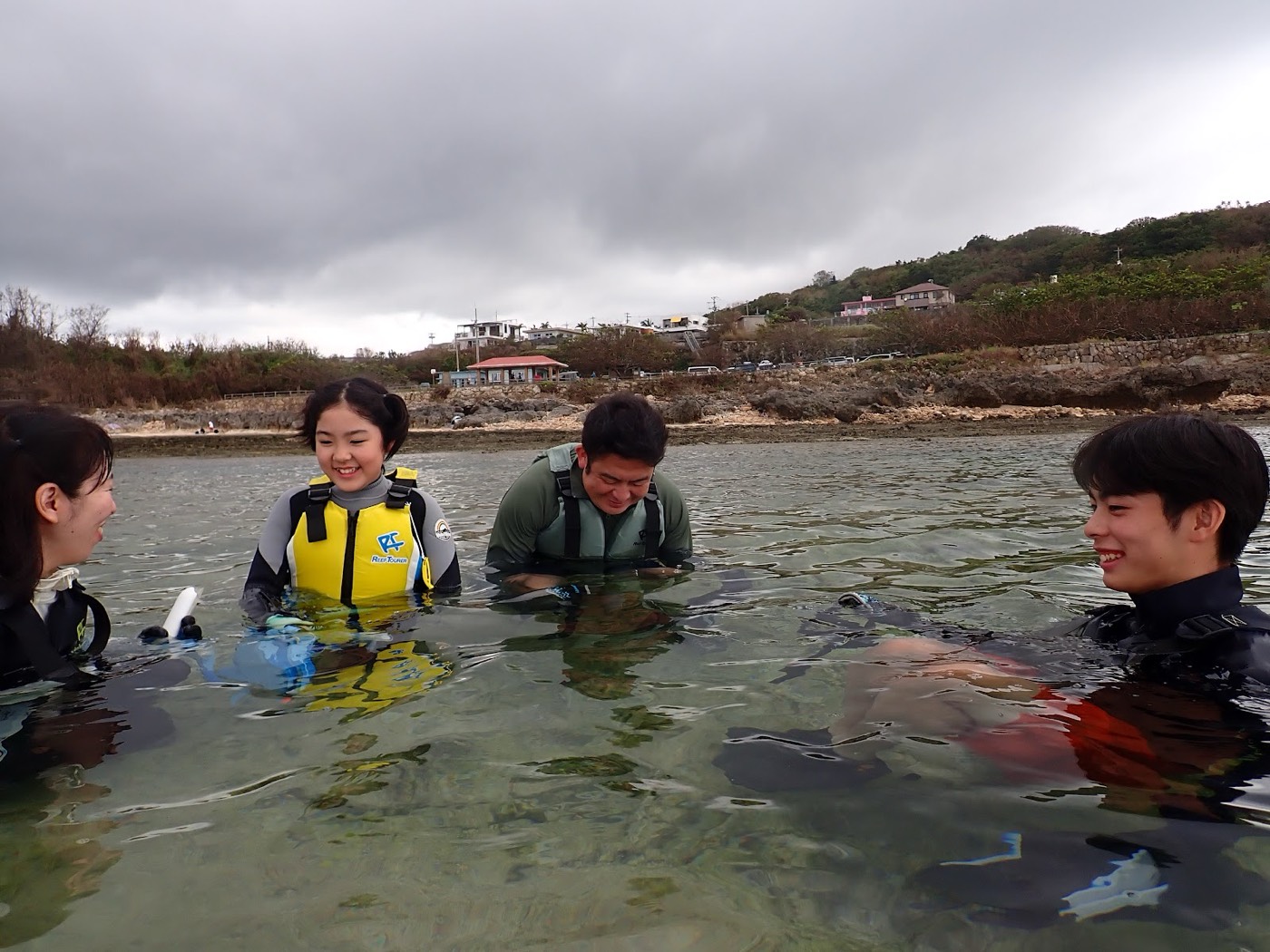 浅瀬で大人のグループと子供が笑顔で水面に浮きながら会話する様子