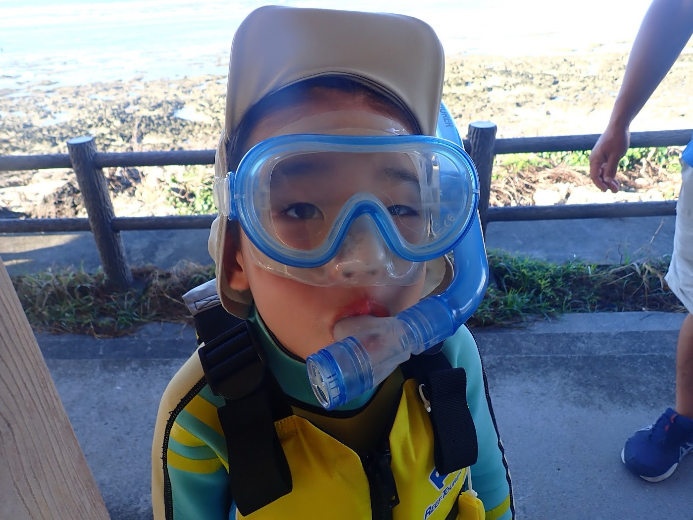 天然水族感あふれる青い海を背景に、マスクとシュノーケルを装着する子供の顔