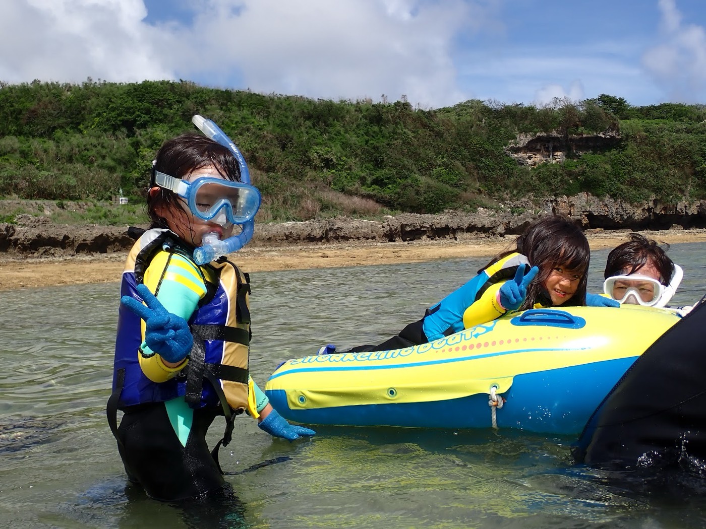 天然水族感。青い空と緑豊かな海岸を背景に、浮き輪に乗った小さなお子様が海に浮かぶ