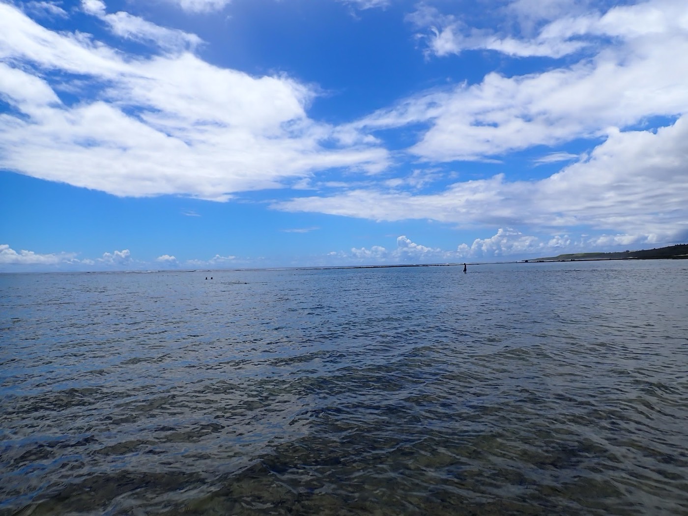 水面越しに広がる青空と沖の遠浅リーフが見える海の風景