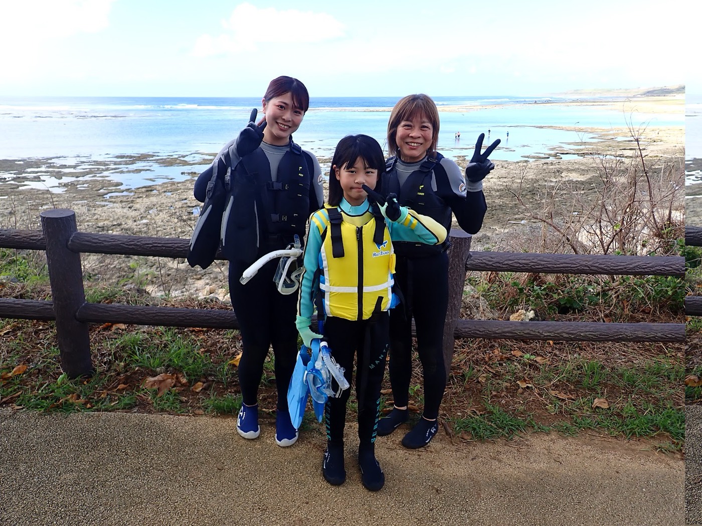 天然水族感あふれる海岸線を背に、参加者と担当の池田が笑顔でポーズをとる