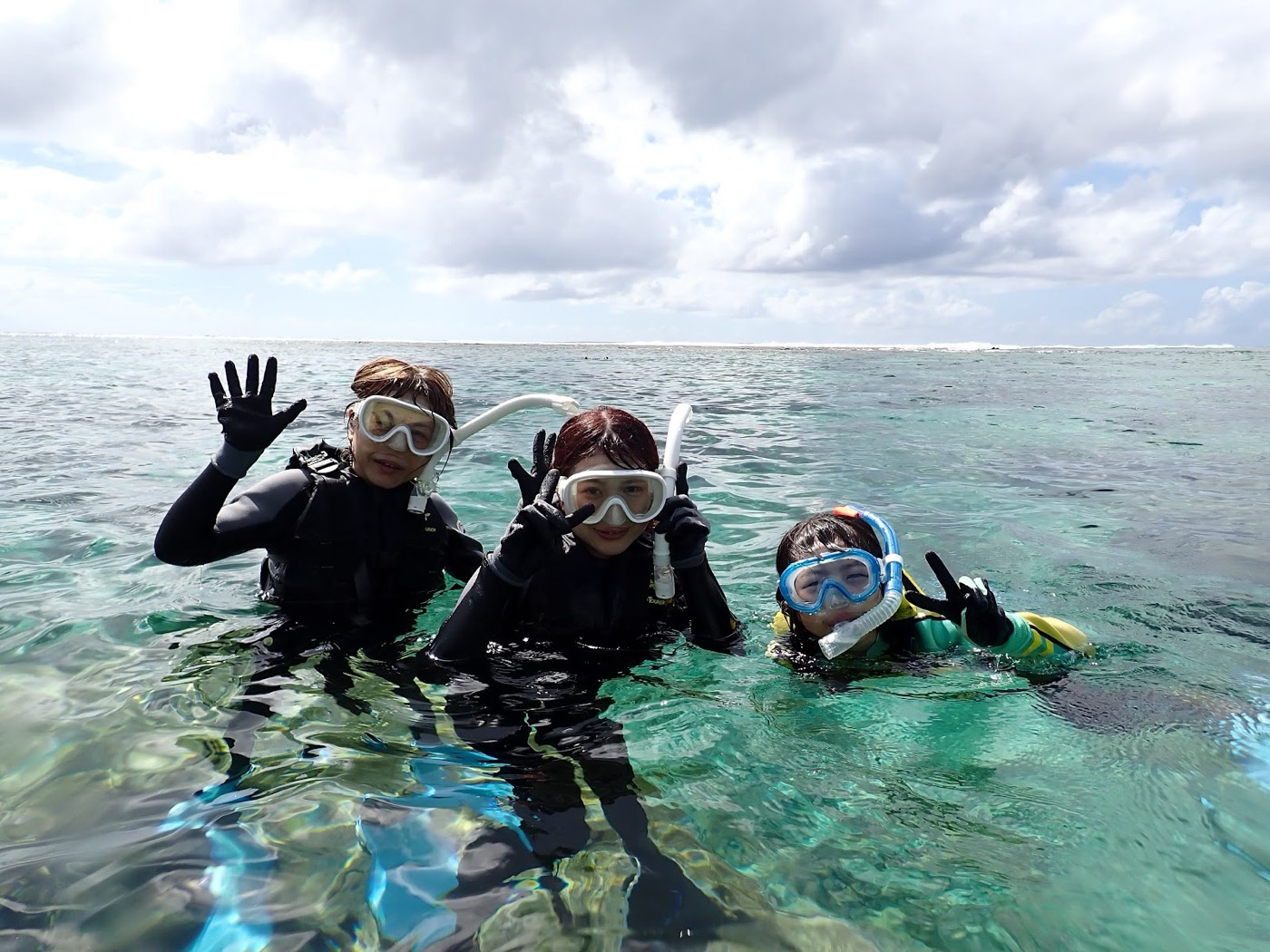 海に入り、水面から顔を出してピースサインをする参加者と担当の池田