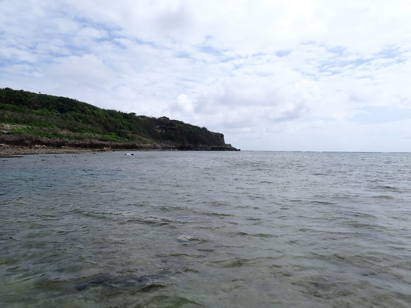 天然水族感で紹介する、大度海岸の広がる穏やかな海面と、青い空、緑の崖。『天然水族館』の美しい自然が広がる