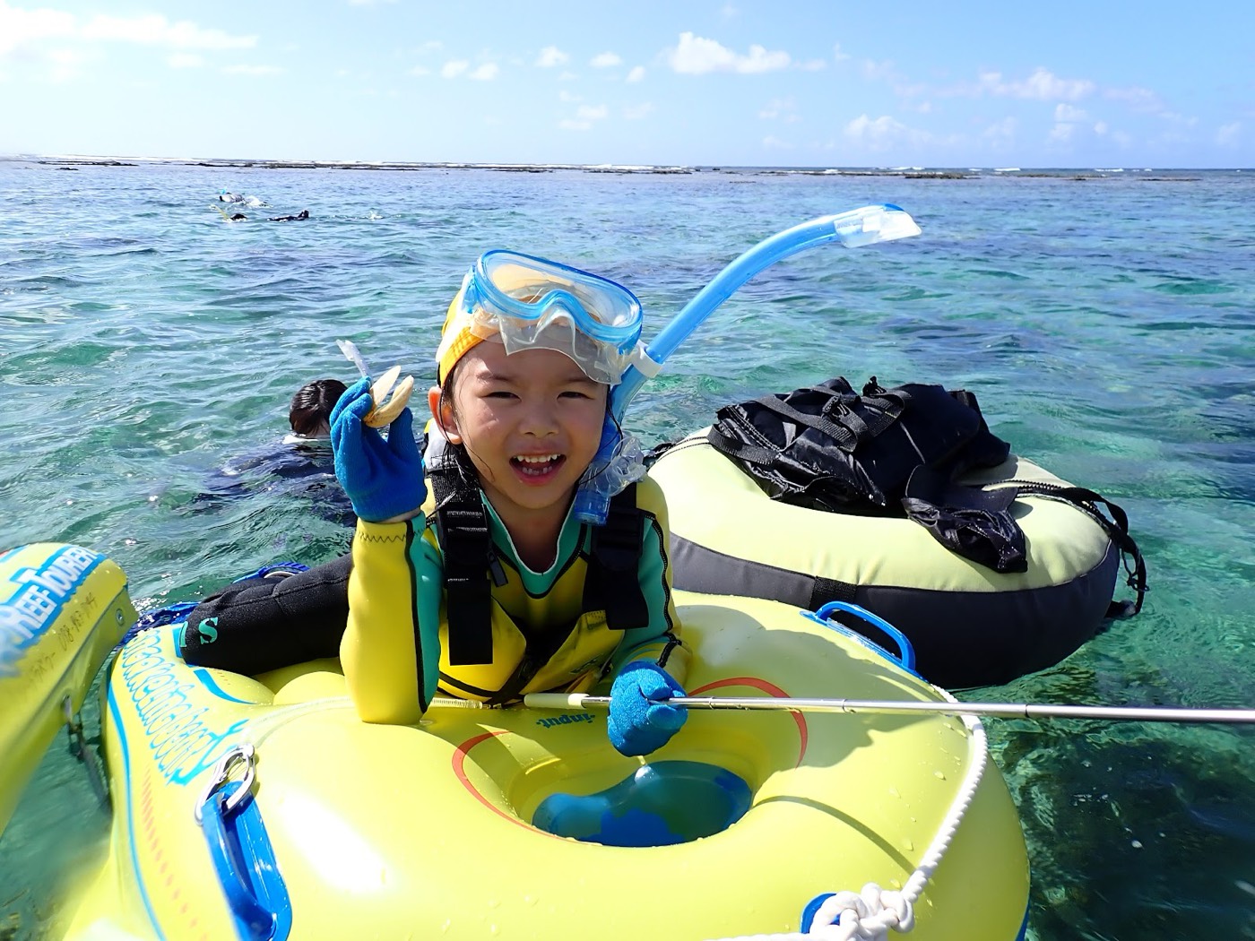 浮き具に乗り海から顔を出し笑顔でピースするお子様